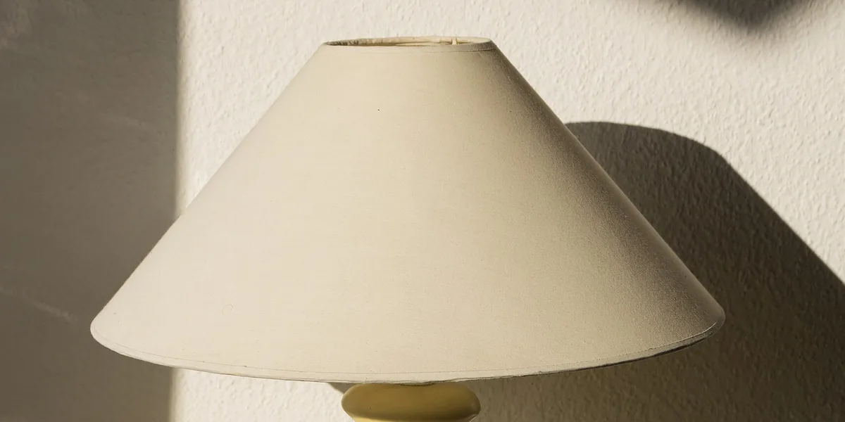 Heller Stoffschirm einer gelben Lampe an der Wand